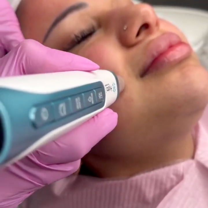 Dr. Pen H6 microneedling pen being used during a facial treatment on a client's cheek.